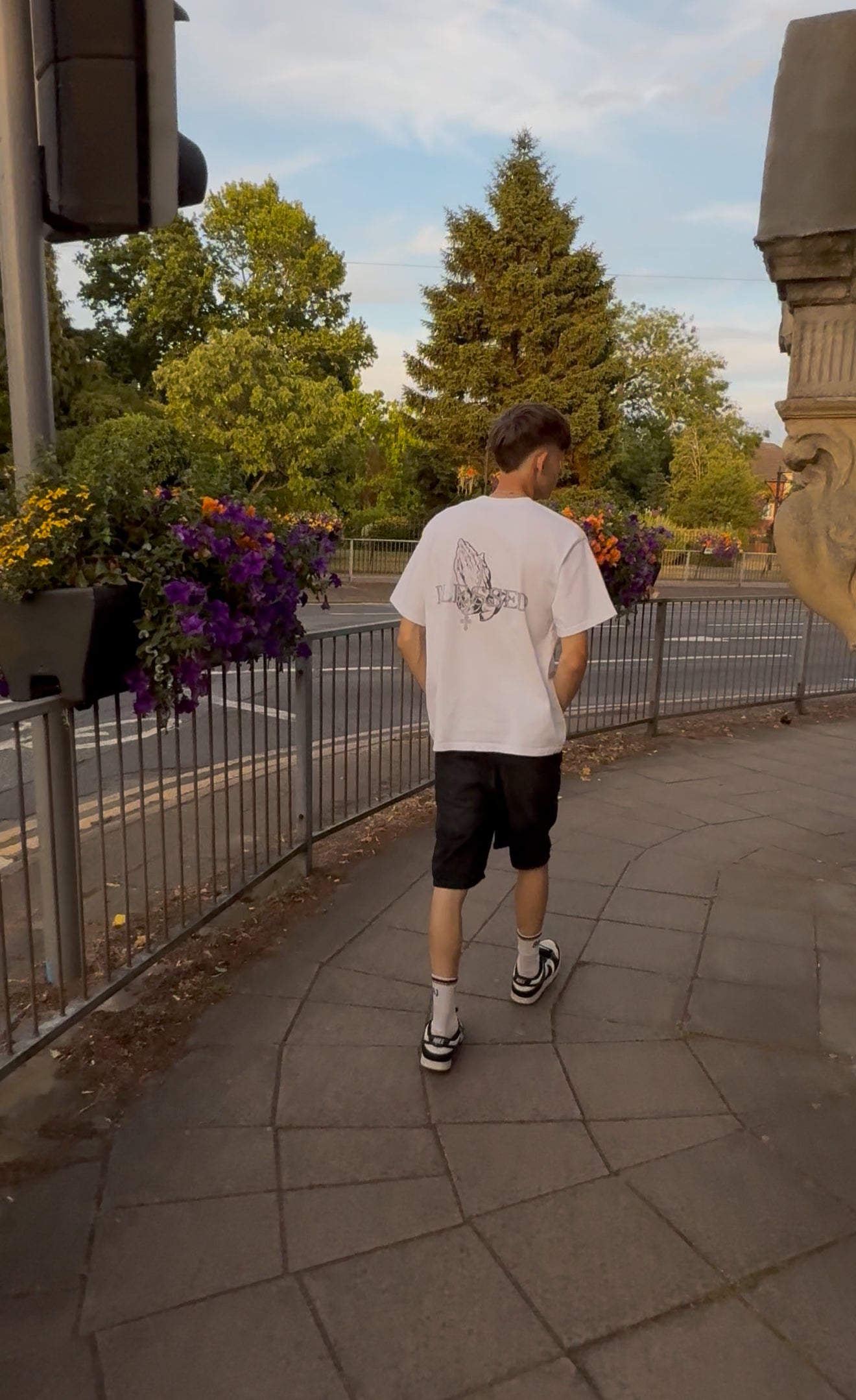 Person walking on a path with Blessed T-Shirt on, with trees and flowers in the background